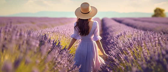 Keuken foto achterwand Rear view of a young woman in a white dress and hat walking through a purple lavender field. natural background concept © Ton Photographer4289
