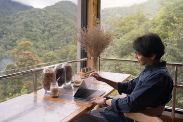 digital nomad concept asian freelancer man use laptop to work at mountain view of coffeeshop