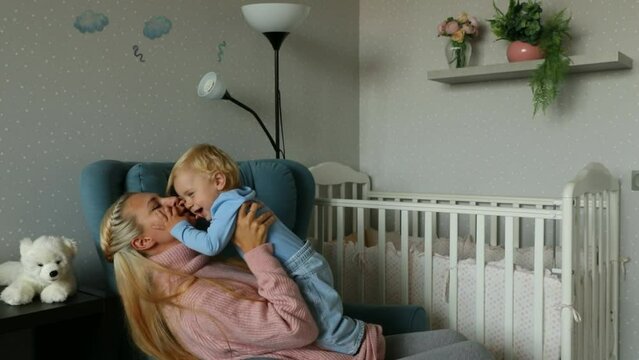 Happy mom and baby kissing, laughing and hugging at home