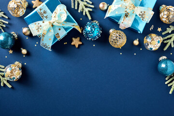 Christmas card. Flat lay glistening blue paper gift boxes, gold and blue Xmas balls ornaments, fir...