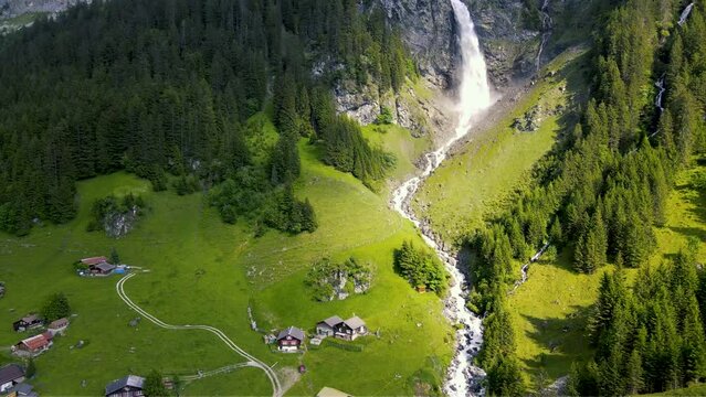 Panoramic aerial view of powerful Swiss waterfall with dramatic sunlight in the Swiss Alps in Sch&auml;chental Swiss Valley in Switzerland featuring, St&auml;ubifall and Idyllic Swiss village of &Auml;sch near Klaus