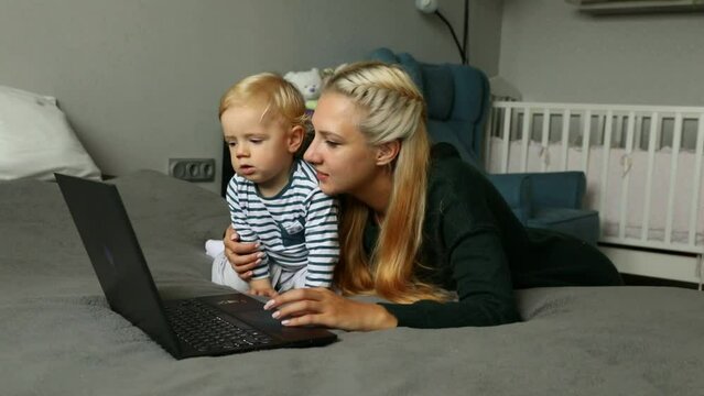 Mom with kid with computer at home on the bed