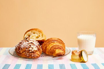Continental breakfast. Almond flavored crispy croissant with honey and milk over beige background....