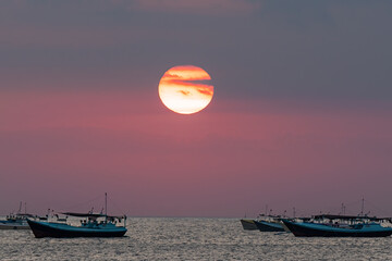 Coucher du soleil avec en fond des pirogues à balancier indonésiennes sur la plage de Kedonganan, à Bali