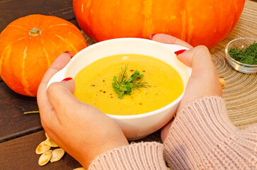 Pumpkin hot soup puree and pumpkins on a wooden table