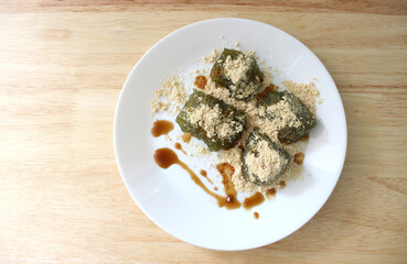 Matcha Warabi Mochi with Kinako powder and brown sugar syrup in white plate on wooden table, traditional Japanese dessert