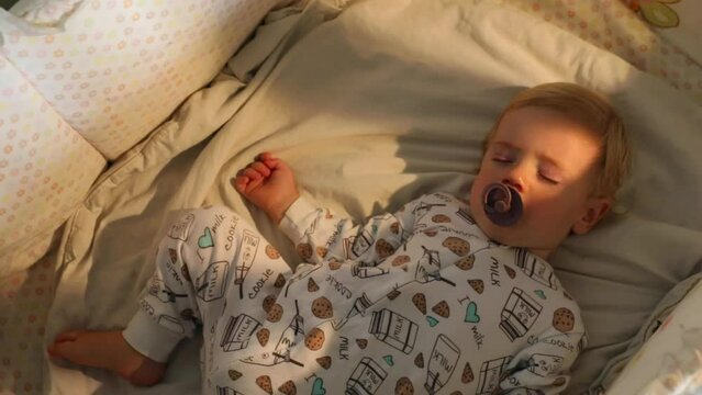 Baby with pacifier sleeping in crib
