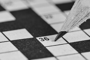 Simple pencil on background of crossword puzzle closeup.