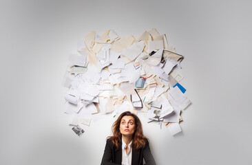 Documents cloud. Tired and sad young woman sitting under a cloud of documents. Visualization of tasks and thoughts. Office items. White background. Copy space. Generative AI