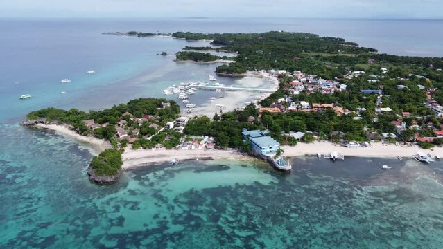 Malapascua Island in an aerial long shot with Dive resorts on logon and bounty beach as Diving Boats at the pier, Philippines