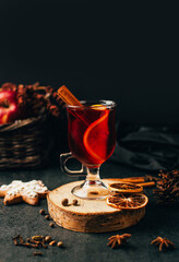 close-up of a glass with mulled wine cinnamon and cardamom on a black background with ingredients for the drink