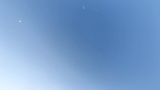 A teenager child on the beach jumps somersault over the camera. View from the bottom of the top to the child jumping, blue sky and splashing water