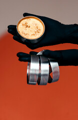 Cookies in shape are held by the hands of a pastry chef in black gloves on an orange background