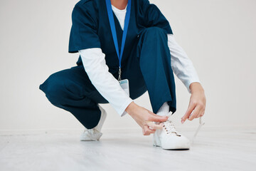 Healthcare, shoes and tie with hands of a nurse in studio while getting ready for medical service...