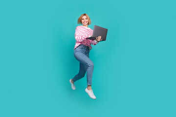Full length photo of positive cheerful lady wear pink pullover communicating device jumping isolated turquoise color background
