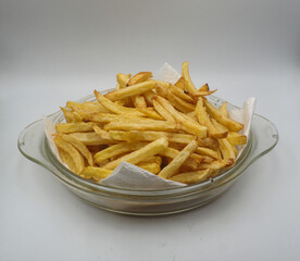 Fried potato chips in a glass dish on a white background