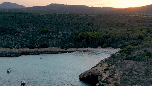 Drone footage of the sandy beach and Cala Varques Bay at sunset in Mallorca, Balearic Islands, Spain