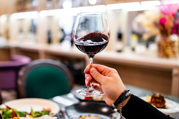 Young man hand holding a glass with red wine in a restaurant