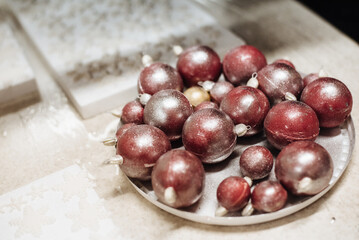 Chocolate Christmas balls on a white plate on the table. Chocolate decoration for New Year's cake. Handmade candies.