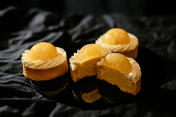 Lemon tartlets on a black background. An exquisite European dessert with fruit filling.