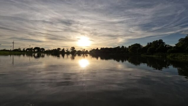 Evening sunset view by a natural pond, clouds moving slowly, time lapse.