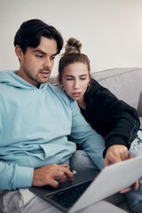 Laptop, stress and couple pointing in home living room for budget planning, taxes or debt. Computer, man and frustrated woman on sofa for finance, asset management and mortgage, loan and rent bills