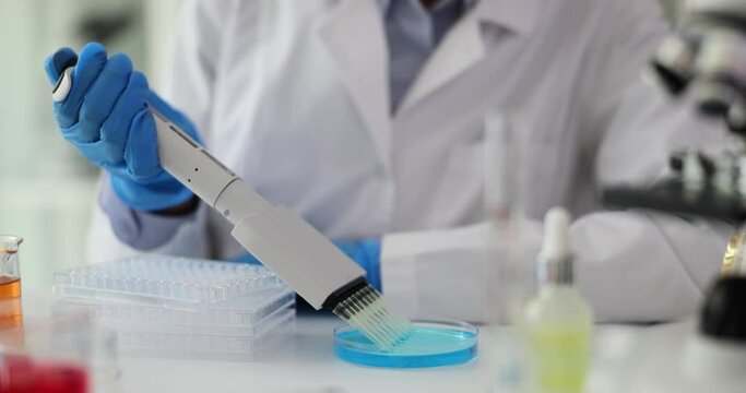 Laboratory worker drops liquid using special tool into container. Multichannel pipette tips filled in with reaction mixture to amplify DNA in plastic wells