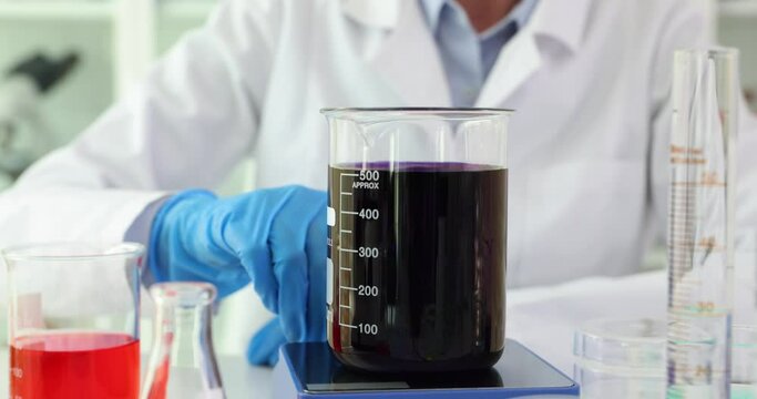 Scientist flask with boiling black solution in lab. Magnetic stirrer moves toxic solution and boils it