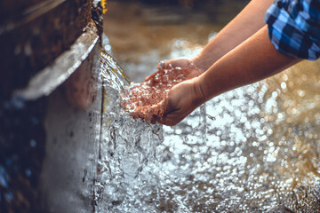 Hands scoop up clear water from a forest spring. A man drinks water from a beautiful clean natural...