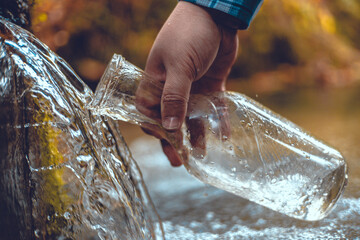 Close-up of a man collecting spring water into a transparent bottle A beautiful natural source of...