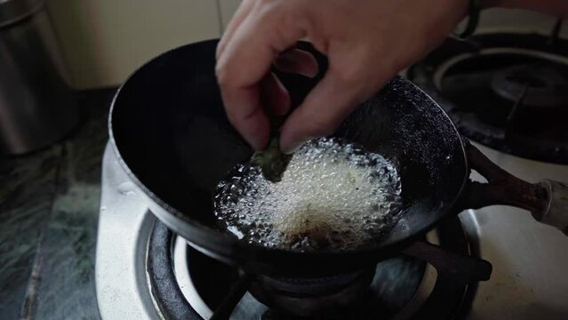 indian woman deep frying bhajiya or alu vadi in oil. alu vadi patra or ptrode maharashtrian and gujarati snack. 