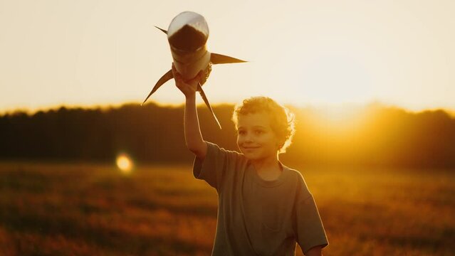 Carefree Little Boy Playing With Toy Rocket In Field In Sunset And Dreaming About Space Traveling