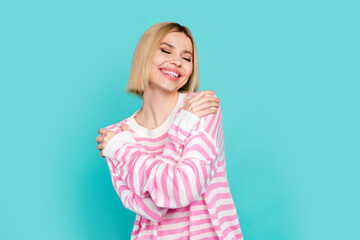 Photo of cute adorable lady wear pink pullover hugging herself closed eyes empty space isolated turquoise color background
