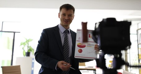 Business vlog and video coaching and presentation on analytics. Confident smart male expert showing financial statistics to camera - Powered by Adobe