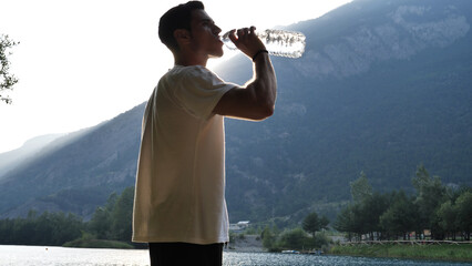 A man drinking water from a plastic bottle. Photo of a man quenching his thirst with a refreshing...