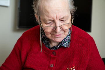 Indoor portrait of an 85 yo white woman reading, Tienen, Belgium