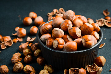 Hazelnuts in a black stone bowl. Side view. Full frame of heap of hazelnuts. Close up.