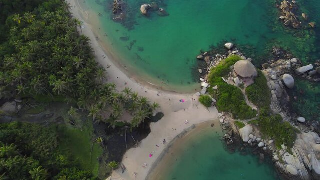 Tropical beach coastline and Cabo de San Juan bungalow in Tayrona at sunset. Aerial top down