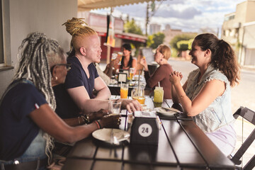 Group of different ages chatting at a table in an outdoor bar.