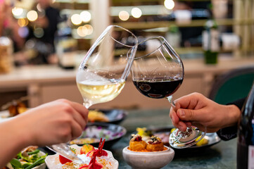 Close up of hands young couple man and woman clinking with glasses of red and white wine at restaurant