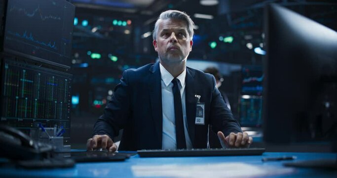 Portrait of a Middle Aged Man Working on the Floor in a Modern Stock Exchange Firm: Specialist Monitoring Listed Companies and Funds, Unit Trusts, Derivatives, Pooled Investment Products and Bonds