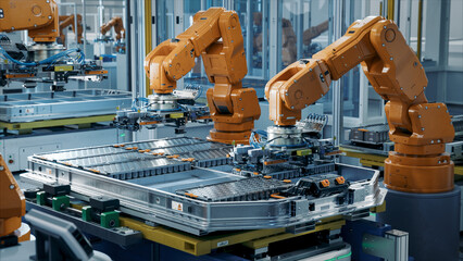 Orange Industrial Robot Arms Assemble EV Battery Pack on Automated Production Line. Row of Advanced...