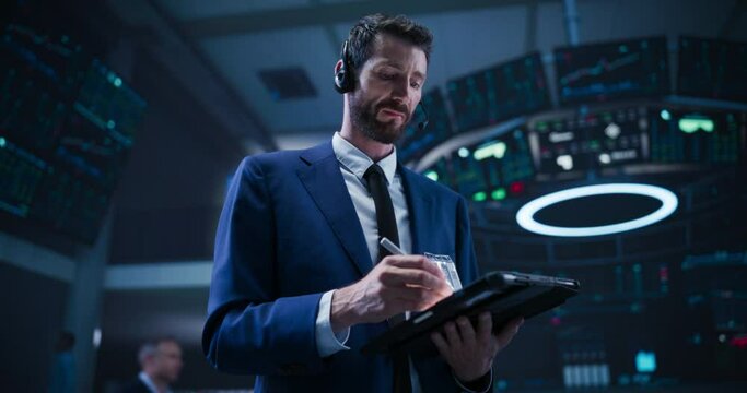 Low Angle Portrait of a Successful Stock Exchange Manager Working in Modern Office. Proactive Trader Browsing Internet on a Tablet Computer, Using Software with Stock Market Auction Operators