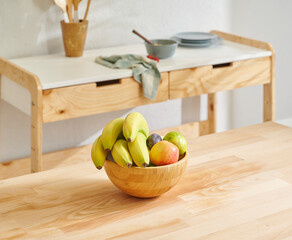 Close up fruit basket on the wooden table, kitchen background, banana, apple and pear.