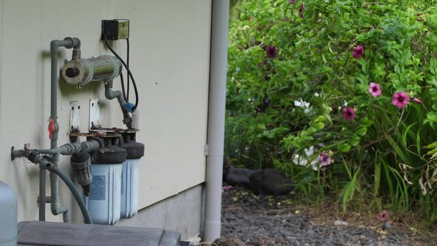 The off grid water filter system seen fitted to the side of a home using UV light and physical filtration and including a digital monitor screen