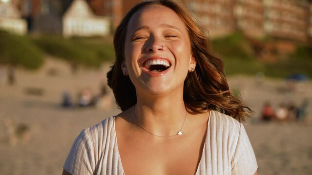 Slow motion shot of a beautiful woman smiling and laughing on the beach at sunset