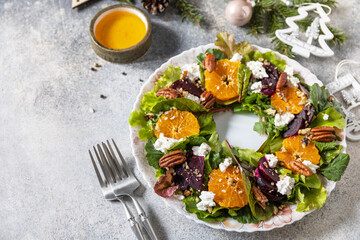 Christmas appetizer. Christmas wreath salad with beetroot, tangerines, feta cheese and pecans on the festive table. Copy space.