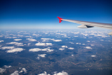 Airplane wing above clouds against clear blue sky. - 661410295