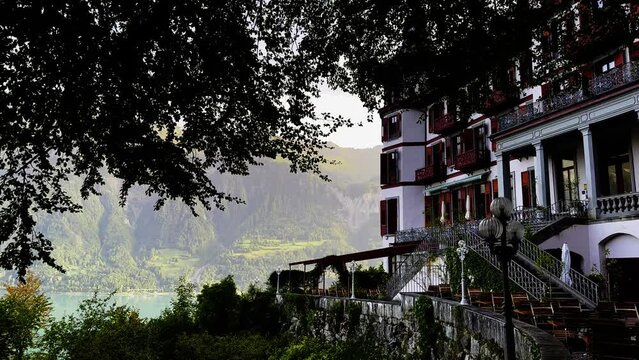 Panoramic View over Giessbach Historical Grandhotel and Lake Brienz with Tree Branch and Mountain in a Sunny Summer Day in Giessbach, Brienz, Bernese Oberland, Bern Canton, Switzerland.