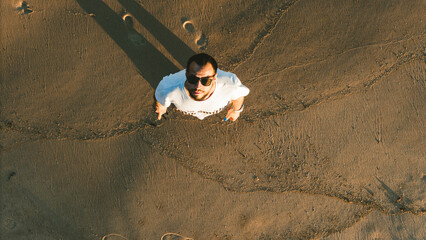 overhead view from a drone as a young man looks up. The person is wearing sunglasses and is dressed...